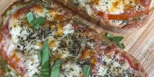 Twee Caprese toasts met gesmolten mozzarella, tomaat, pesto en verse basilicum op een plank