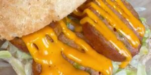 Krokant broodje met kipgrillworst, ijsbergsla en cheddarsaus