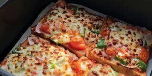 Vier goudbruin gebakken broodpizza’s met mozzarella, paprika, tomaat en rode ui in een Airfryer