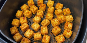 Goudbruin gebakken blokjes gekruide tofu in de mand van een Airfryer