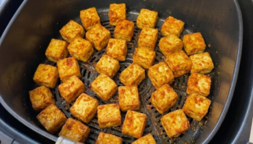 Goudbruin gebakken blokjes gekruide tofu in de mand van een Airfryer