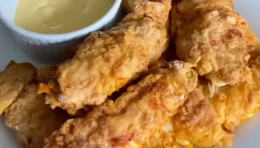 Krokante chicken tenders met een romige dipsaus op een wit bord