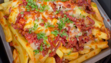 Loaded fries met krokante spekjes, gesmolten kaas en peterselie in een Airfryer-bakvorm