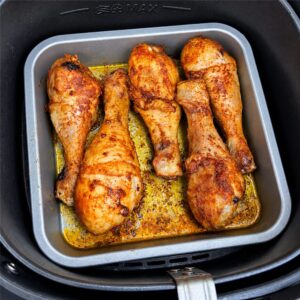 Kippendrumsticks op een vierkante bakplaat in de airfryer
