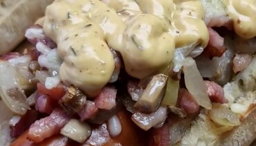 Broodje rookworst met spekjes, ui, champignons, gesmolten kaas en Unox-saus